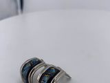 two silver rings with blue and green designs on them sitting on a white table