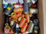 de nombreuses bobines de fil dans une boîte posée par terre