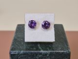une paire de boucles d'oreilles en amethorate posées sur un bloc de marbre