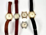 quatre modèles différents de montres-bracelets posés sur un fond blanc