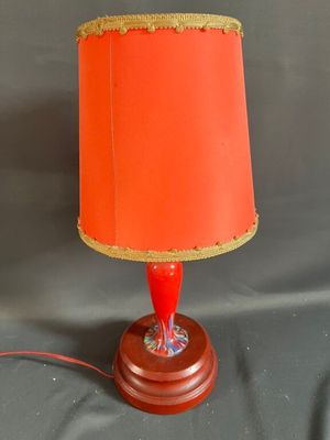 une lampe orange avec un abat-jour rouge posée sur un socle en bois