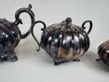 two silver teapots and a sugar bowl sitting on a table