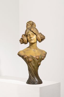 sculpture représentant la tête d'une femme, posée sur un socle devant un mur blanc