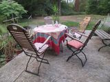 une table et des chaises sur une terrasse, recouverte d'une nappe