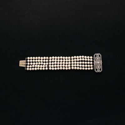 un gros plan d'un bracelet à perles blanches posé sur une surface noire