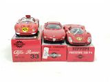 three red toy cars sitting on top of boxes on a white surface