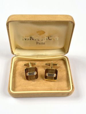 two pairs of cufflinks in a box on a white surface