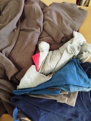 une pile de vêtements posée sur une table, à côté d'un ordinateur portable