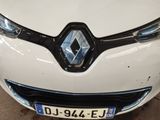 the front end of a white car with a blue and black emblem