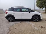 the white car is parked in the parking lot near a tree