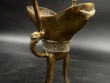 brass statue of a fish holding a spear on a black background