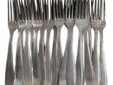 six forks are arranged in a row on a white surface