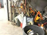 un seau rempli d'outils dans un garage, à côté d'un tas d'autres objets