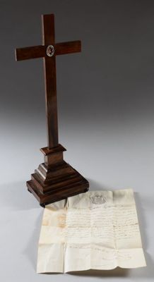une croix en bois posée sur une feuille de papier, à côté d'une autre feuille de papier