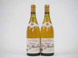 deux bouteilles de vin posées l'une à côté de l'autre sur une surface blanche