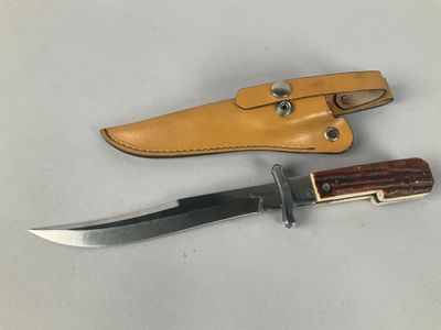 a close up of a knife and sheath on a white surface