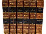 six vieux livres sont alignés sur une surface blanche