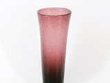 un vase en verre rose posé sur une table blanche