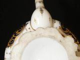 a person holding a white and gold teapot in their hand