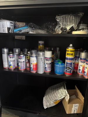 many cans of paint sitting on a shelf in a room