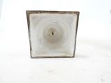 a small square vase with a small candle inside of it
