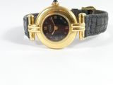 une image représentant une montre-bracelet noire et dorée avec des chiffres romains
