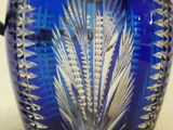 un vase en verre bleu muni d'une anse en argent, posé sur une table