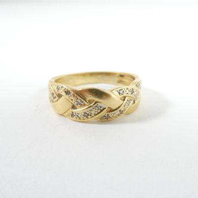 gros plan d'une bague en or avec des diamants sur une surface blanche