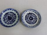 pair of blue and white plates with designs on them sitting on a table