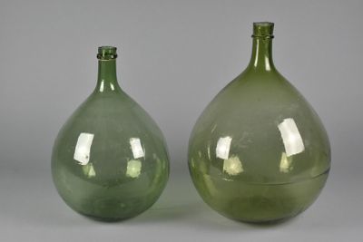 pair of green glass vases sitting on top of a gray surface