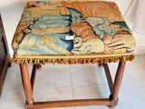 un petit tabouret recouvert d'une tapisserie, dans une pièce