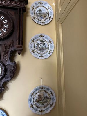 beaucoup d'assiettes accrochées au mur à côté d'une horloge
