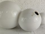 three white vases sitting on a table with a white wall in the background