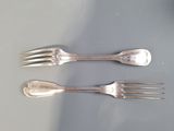 three forks and two spoons sitting on a table