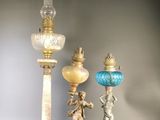 three antique lamps are sitting on a black surface with a gray background