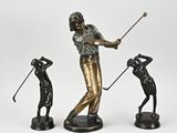 three bronze figurines of a man playing golf and a woman swinging a golf club
