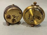 pair of antique brass clock parts on a white surface