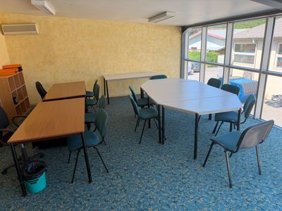 des tables et des chaises dans une pièce dotée d'une grande fenêtre donnant sur un parking