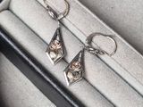boucles d'oreilles en argent et en or dans un coffret noir sur fond blanc
