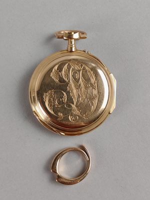 a gold pocket watch and a ring on a table