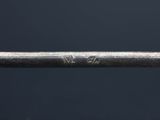a close up of the handle of a silver spoon with the word v on it