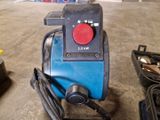 une machine bleue avec un bouton rouge, posée par terre