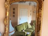 a mirror on the wall above a table with a green couch