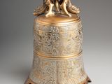 an antique brass bell with a bird on top