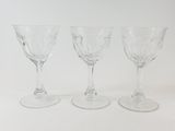 three empty wine glasses are lined up on a white surface