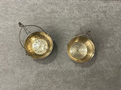 deux petits bols en laiton munis d'anses, posés sur une surface grise