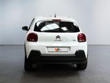 the rear end of a small white car parked in a room