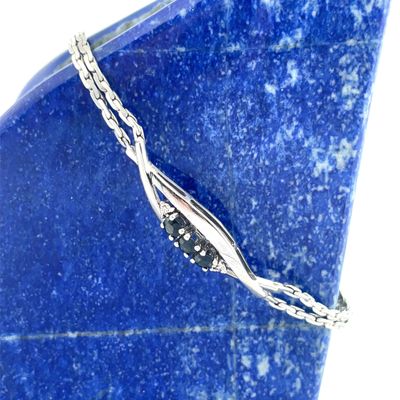 bracelet plaqué argent posé sur une plaque de marbre bleu, avec une chaîne en argent