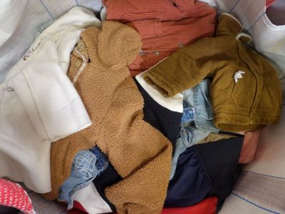 a pile of clothes sitting in a basket on a bed