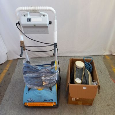 une machine bleue et blanche et une boîte posée par terre